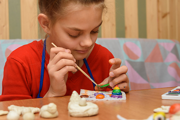 Image showing A girl at home paints a craft made from salt dough