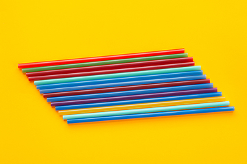 Image showing A dozen multi-colored cocktail tubes lie on a yellow background