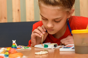 Image showing A girl enthusiastically paints a puff pastry craft with watercolors