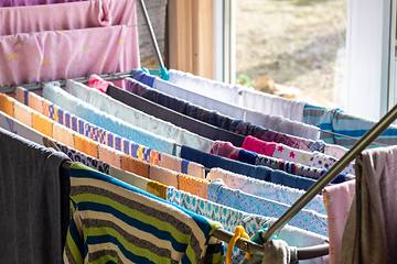 Image showing The washed clean linen is dried in a dryer near the window