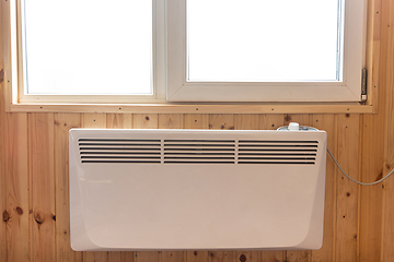 Image showing Electric radiator under the window of a country house whose walls are finished with clapboard