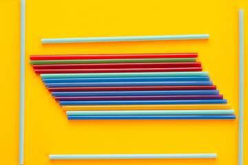 Image showing A bunch of multicolored cocktail tubes lies on a yellow background