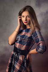 Image showing Portrait of a beautiful girl in an interesting checkered dress on a gray background