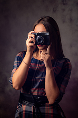 Image showing Girl photographer takes pictures with an old camera, studio photography on a gray background