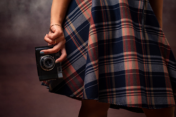 Image showing Girl\'s hand holding a camera at the hem of the dress, studio photography on a gray background