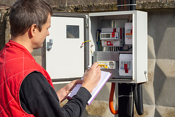 Image showing An energy sales worker takes readings of electricity meters