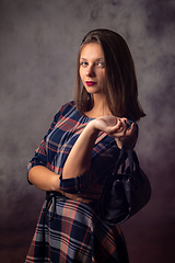 Image showing Portrait of a beautiful girl with a black handbag in her hands