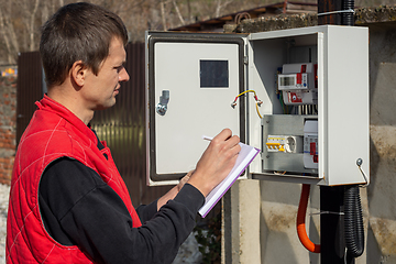 Image showing A resident of a country house takes readings of an electric energy meter