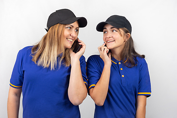 Image showing Mother and daughter are standing with their backs to each other, talking on the phone and looking at each other