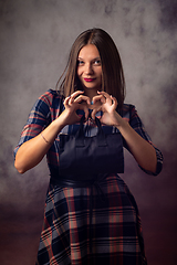 Image showing Portrait of a beautiful girl on a gray background, the girl holds a black handbag in front of her