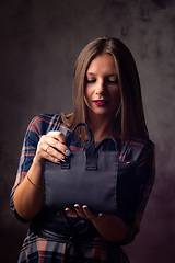 Image showing A beautiful girl holds a handbag in front of her and mysteriously opens it