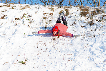 Image showing A girl is rolling down a snow-covered slide upside down