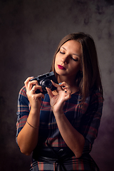 Image showing Girl photographer adjusts the camera, studio photography on a gray background