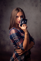 Image showing Girl photographer holding an old camera in her hands, studio photography on a gray background