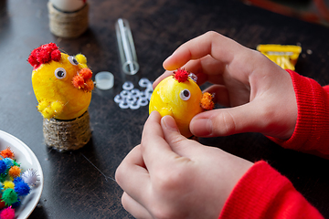 Image showing Children\'s hands make a craft from an egg for the Easter holiday