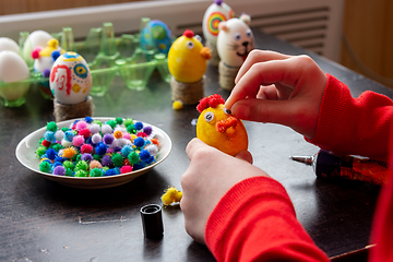 Image showing A child glues an eye to the shape of a chicken for Easter