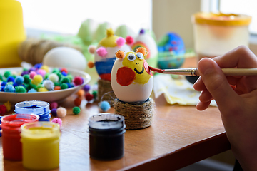 Image showing Child\'s hand draws a funny face on Easter egg