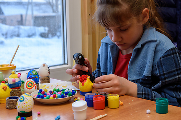 Image showing A girl glues a decorative element to a craft with a glue gun