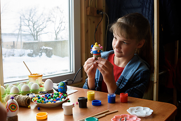 Image showing The girl carefully examines the chicken egg craft