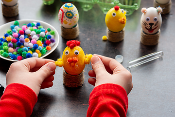 Image showing Children\'s hands made a chicken craft out of an egg, there are other figures in the background