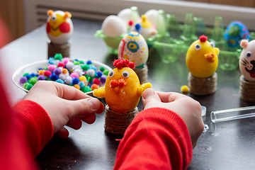 Image showing The child finishes making another egg-shell figurine to celebrate Easter