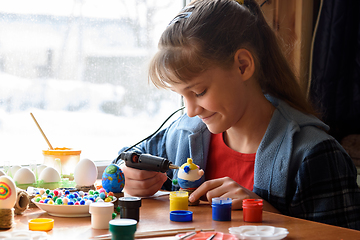 Image showing A girl glues elements to crafts with a glue gun