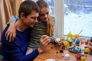 Image showing Father and daughter paint easter eggs while sitting at the table by the window