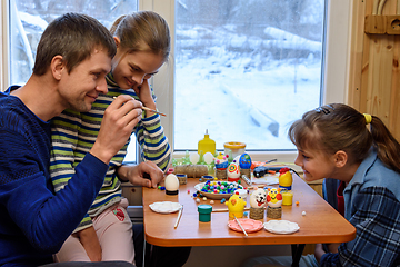 Image showing Dad and two daughters paint Easter eggs while sitting at the table by the window