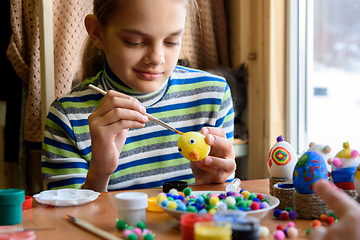 Image showing A twelve-year-old girl paints Easter eggs for the holiday