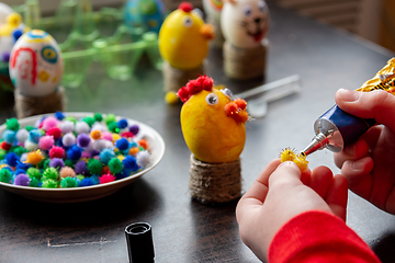 Image showing Children\'s hands apply glue to the egg craft element