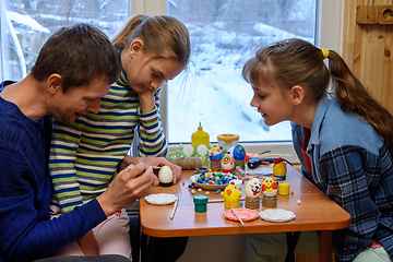 Image showing Children carefully watch their dad paint eggs