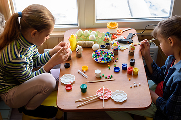 Image showing Two girls at the table are painting Easter eggs