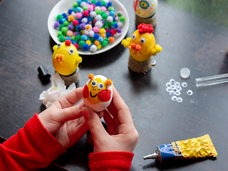 Image showing The girl is holding a beautifully painted egg with a smiling painted face