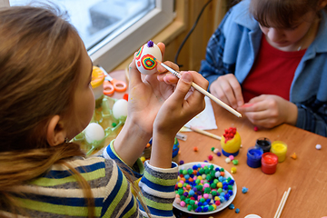 Image showing Children at the table are painting Easter eggs for the holiday