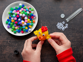 Image showing Childrens hands make chicken from eggshell for easter holiday, top view