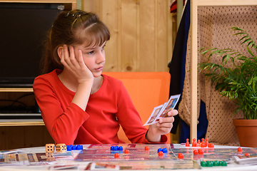 Image showing The girl plays board games and is thoughtful holding cards in her hand