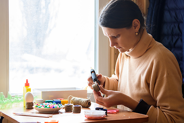 Image showing Girl decorates crafts while sitting at home by the window