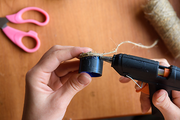 Image showing Girl\'s hands decorate crafts using twine and hot melt glue, close-up