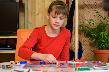 Image showing A girl makes another move with chips while playing a board game at the table