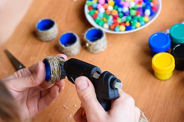 Image showing The girl\'s hands make crafts from twine and a glue gun