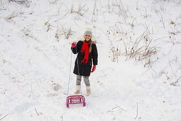 Image showing A girl with a sled stands in a snowy meadow