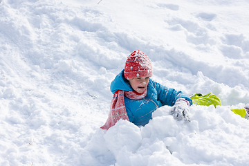 Image showing The girl who rolled down the hill has all her face and a hat in the snow