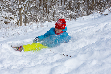 Image showing The girl slid down the hill into a snowdrift and squeezed her eyes from the snow flying into her face