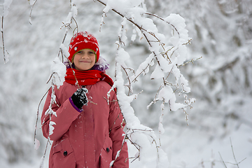 Image showing Happy girl stands in a snowy forest under a snowy branch