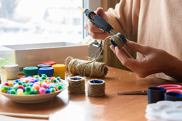 Image showing Girl\'s hands decorate crafts using twine and hot melt glue