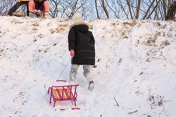 Image showing A girl runs with a sled up the hill