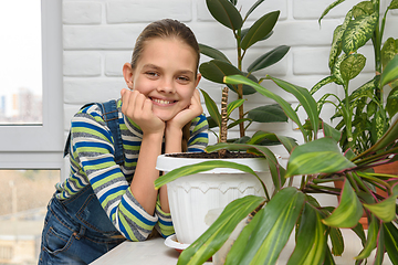 Image showing A girl examines indoor flowers and turns and looks into the frame