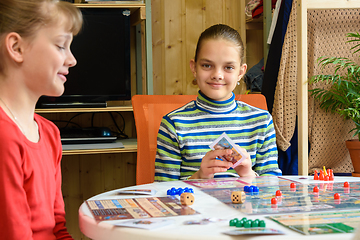 Image showing Children in a good mood are playing a board game, one of the girls looked into the frame