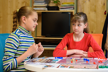 Image showing A girl is waiting for another girl to make another move while playing board games