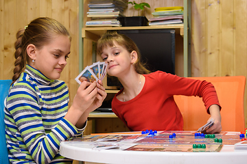 Image showing Children play a board game, one of the girls peeps at the cards of the other